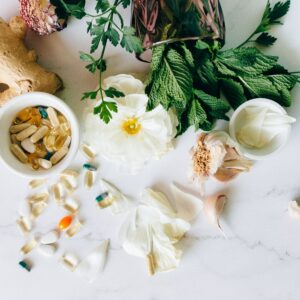 Supplement capsules and herbs in front of a white background